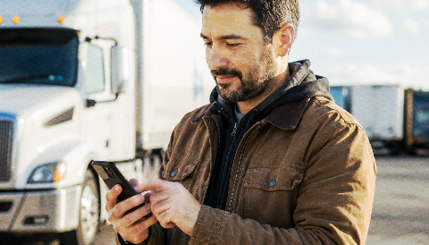Carrier using a mobile phone beside a truck.