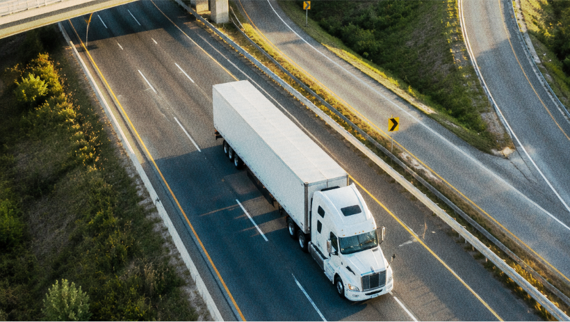 Truck driver using a mobile phone beside a semi-truck.