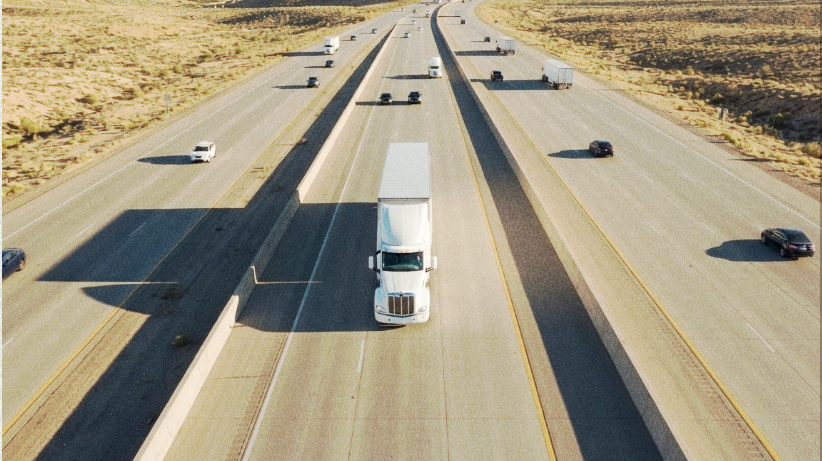 Truck driver using a mobile phone beside a semi-truck.