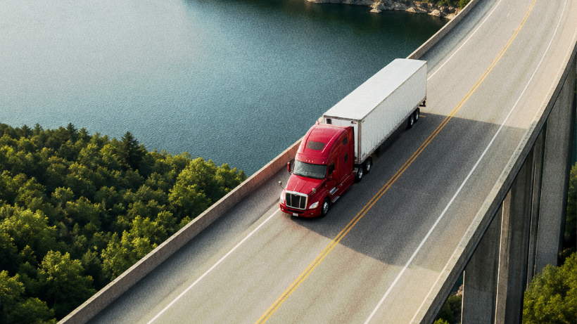 Truck driver using a mobile phone beside a semi-truck.