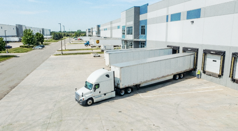 Truck driver using a mobile phone beside a semi-truck.